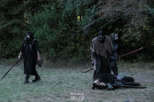 Personaggi mascherati durante una scena nella radura, Exclave settembre 2026